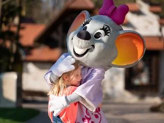 Kind umarmt das Maskottchen des Europa-Park, Edda Euromausi. 