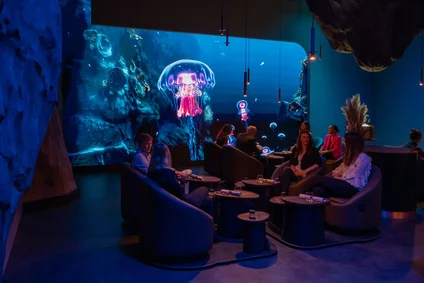 Visiteurs installés dans les Floating Chairs de la salle Ocean d’Eatrenalin, devant le grand écran LED.