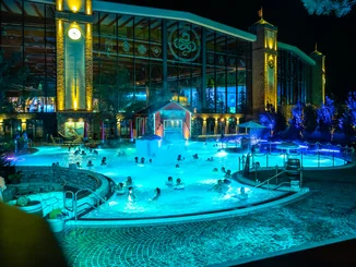 Der beheizte Außenpool Frigg Tempel der Wasserwelt Rulantica im Dunkeln. Gäste plantschen vergnügt und die Beleuchtung taucht das Becken in eine magische Atmosphäre.