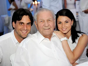 Thomas, Katja and Franz Mack pose for a group photo in white clothing, with Franz Mack standing in the middle.