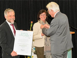 Klinikleiter Stephan Maier (links) übergibt gemeinsam mit dem Vorsitzenden des Kreis- und Bezirksverbands der Arbeiterwohlfahrt, Hansjörg Seeh, die silberne Ehrennadel und die Ehrenurkunde an Marianne Mack.