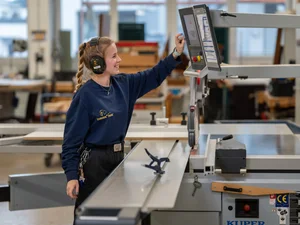 Mitarbeiterin der Schreinerei im Europa-Park Erlebnis-Resort bei der Arbeit an einem Schneidegerät.