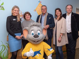 Prof. Spiekerkötter, Charlotte Niemeyer, Roland Mack, Ann-Kathrin Mack und Charles R. Botta vor einer bunt bemalten Wand in der Kinderklinik Freiburg.
