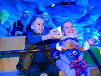 Kinder sitzen gemeinsam mit ihren Eltern und einem Snorri Plüschtier in der Attraktion Snorri Touren im Europa-Park. 
