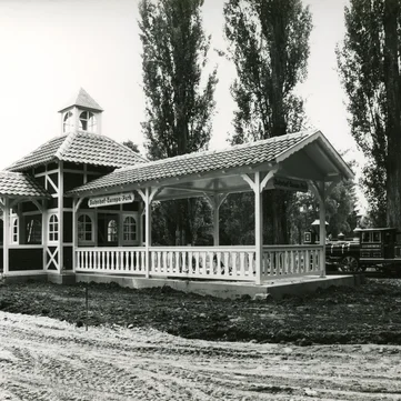 Schwarzweißaufnahme des Panoramabahn-Stationsgebäudes mit einfahrendem Zug und Baustelle um das Gebäude herum.