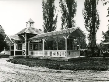 Schwarzweißaufnahme des Panoramabahn-Stationsgebäudes mit einfahrendem Zug und Baustelle um das Gebäude herum.