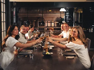 Gäste am Tisch stoßen mit Weingläsern im Restaurant Amitié – La Cuisine du Château an.