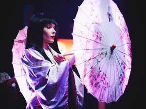 Eine Tänzerin der Europa-Park Dinner-Show mit auffälligem Kostüm und einem Sonnenschirm.