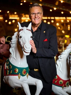 Roland Mack steht neben einem Holzpferd des historischen Salonkarussells Eden Palladium.