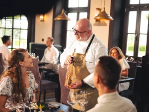 Ein Sommelier schenkt Wein ein und berät Restaurantgäste im Amitié – La Cuisine du Château.