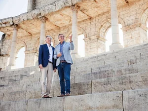 Die Brüder Roland und Jürgen Mack stehen auf dem Kolosseumbogen im Innenhof des 4-Sterne Superior Erlebnishotels "Colosseo".