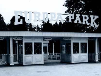 Ancienne entrée principale d'Europa-Park avec quatre guichets et une inscription, entourée de grands arbres.