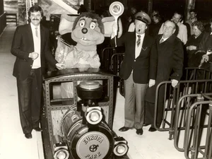 Eröffnung des Alpenexpress mit Zug in der Mitte, Roland Mack links, Franz Mack rechts und Gästen im Stationsgebäude.
