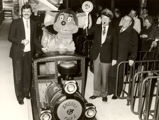 Eröffnung des Alpenexpress mit Zug in der Mitte, Roland Mack links, Franz Mack rechts und Gästen im Stationsgebäude.