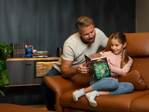 Ein Mann liest mit einem Kind den zweiten Band der Rulantica Saga.