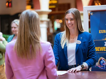 Une collaboratrice du service Recrutement d’Europa-Park Resort discute avec une candidate potentielle à un stand d'information.