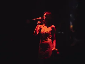 Eine Frau singt im Dunklen, sie wird nur von einer Lampe beleuchtet.