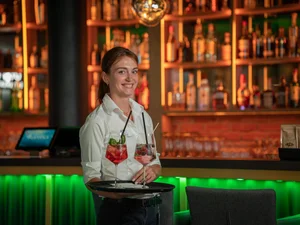 Mitarbeiterin im Europa-Park Erlebnis-Resort transportiert zwei leckere Cocktails auf einem Tablett.