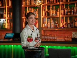 Mitarbeiterin im Europa-Park Erlebnis-Resort transportiert zwei leckere Cocktails auf einem Tablett.