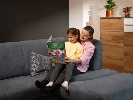 Mutter liest ihrer Tochter aus dem Buch der Kinderbuchreihe Fina & die Yomis vor.