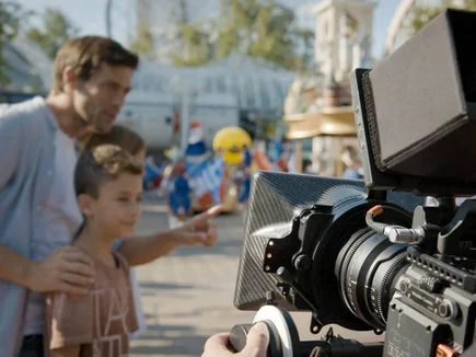 Mann und kleiner Junge stehen vor einer professonellen Videokamera im Europa-Park und werden gefilmt.