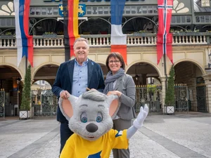 Roland Mack steht gemeinsam mit seiner Frau Marianne Mack und Ed Euromaus vor dem Haupteingang des Europa-Park.