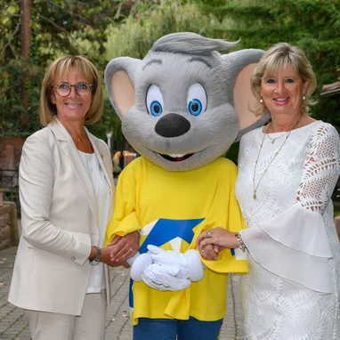 Marianne and Mauritia Mack with Ed Euromaus against a backdrop of trees and flowers.