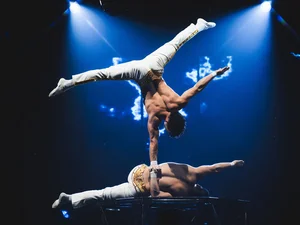 Ein Akroabt der Europa-Park Dinner-Show stützt sich, auf einer Hand stehend, auf der Hand seines Kollegen ab.